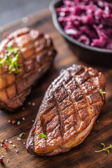 Detail of tasty roasted duck breasts and stewed red cabbage on a wooden cutting board
