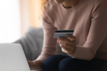 Crop close up of young woman client hold plastic credit card make purchase or pay taxes bills on laptop, female shopping online on computer, enter bank details, use internet service system for payment