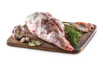 Uncooked lamb chop on a cutting board surrounded by seasonings on an isolated white background