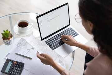 Close up top view of concentrated woman work on laptop manage family expenditures expenses using...