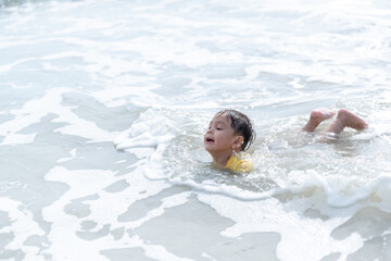 Portrait of little boy splashing in ocean waves