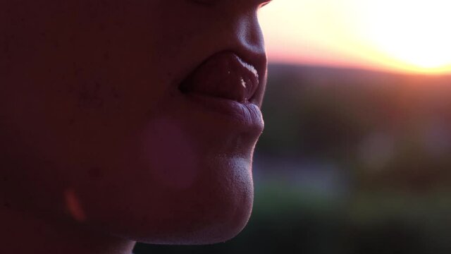 A man licks his lips, as a symbol of flirting, anticipation or just moisturizing them, close-up.