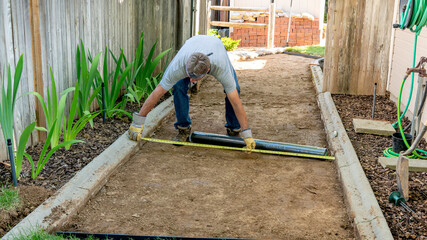 Man takes a measurement of a dirt ground at the beginning of a project