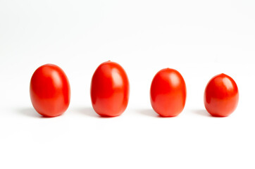 Fresh ripe red cherry tomatoes in straight line on white background