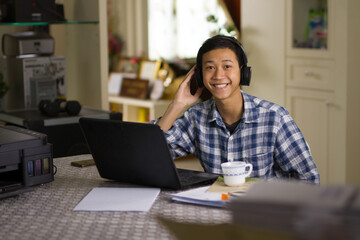 Happy young asian man smiling and look to camera in front of laptop computer online lesson and study at home concept.