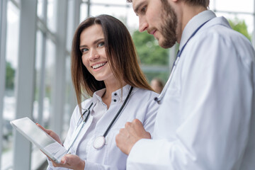 Male doctor using digital tablet with female colleague in hospital, working together.