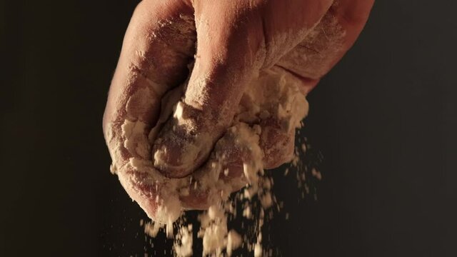 Cook's hand sprinkles flour or icing sugar on a dish, close-up
