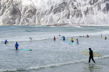 Young men surfing in arctic conditions at Flakstag Beach, Lofoten, Norway, Europe