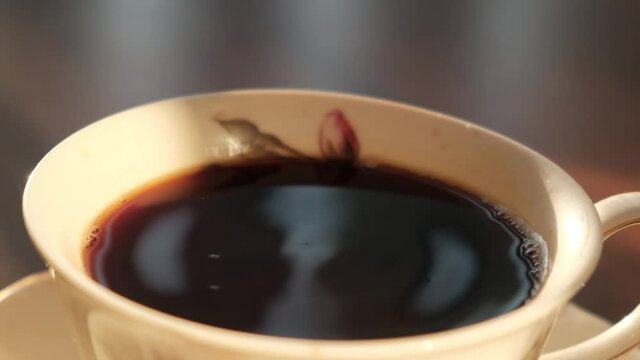 A drop of aromatic coffee falls into a cup, slow motion