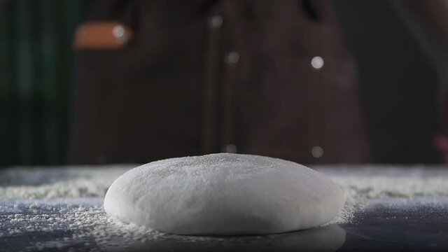 Chef drops dough on flour