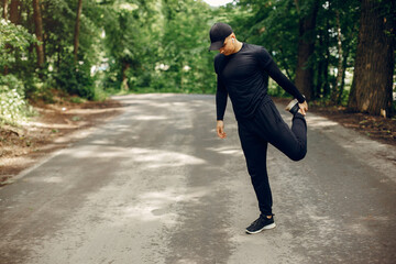 Handsome man in a park. Sportsman in a sportswear. Guy training