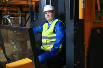 forklift driver in a warehouse looks at the camera.