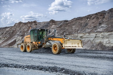motor grader levels the ground on background of sandy slope on the road construction
