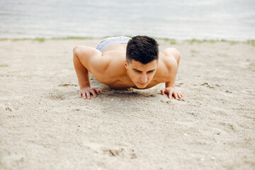 Handsome man on a beach. Sportsman in shorts. Guy training