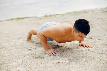Handsome man on a beach. Sportsman in shorts. Guy training