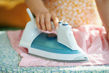female in house in sunny day ironing on ironing board