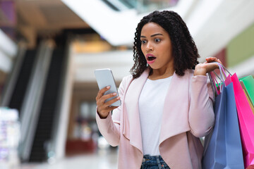 Big Online Sales. Shocked Woman With Smartphone And Shopping Bags In Mall