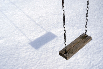 Empty swing in winter time with snow