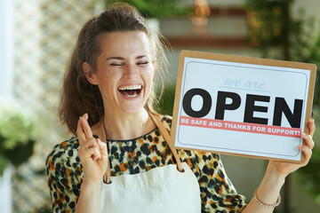 smiling trendy business owner woman in apron showing open sign