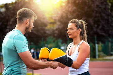 Beautiful handsome healthy young woman sparring with a boxing partner outdoors. Couple in park...