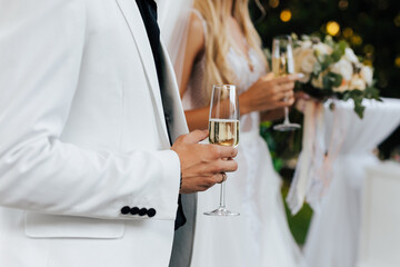 Hands of bride and groom with glasses of champagne. Wedding couple are holding champagne glasses.Celebration wedding toast, party beverage.