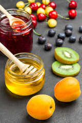 Berries, fruits, honey, jam on black background.