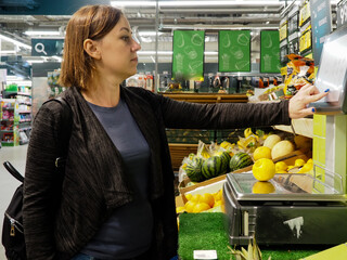 a young woman with a backpack picks up groceries at a grocery store.