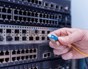 Network engineer working in server room. Connecting network cables to switches