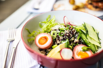 Bowl of fresh poke with avocado, cucumber, boiled egg, salad and seeds