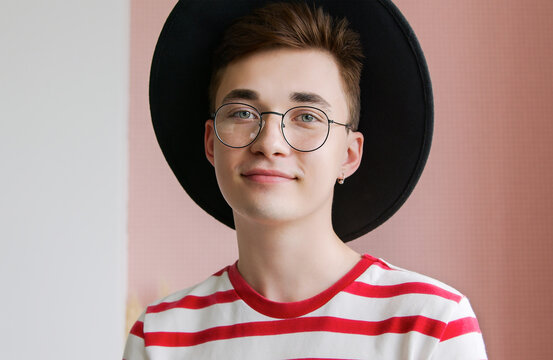Portrait of a young unusual man in a hat and glasses. Hipster guy student designer looking at the camera and smiling. Beautiful stylish people concept.
