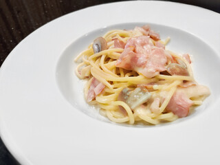 Spaghetti alla Carbonara serving on white plate, spaghetti with pancetta, egg, hard parmesan cheese and cream sauce. Traditional italian dish