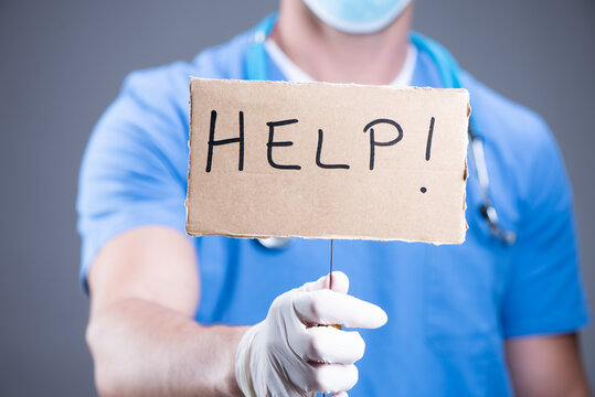 Closeup portrait of health care professional with red tie and stethoscope holding up a sign which says Help