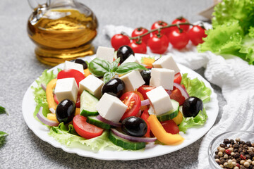 Greek salad with cheese and fresh vegetables on grey background.