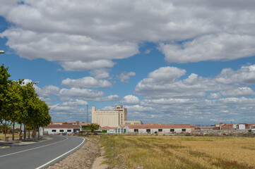 Fototapeta na wymiar road and field with buildings and sky with clouds in Torrijos province of Toledo. Spain