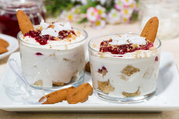 delicious dessert in a glass with cookies, cream and jam, closeup