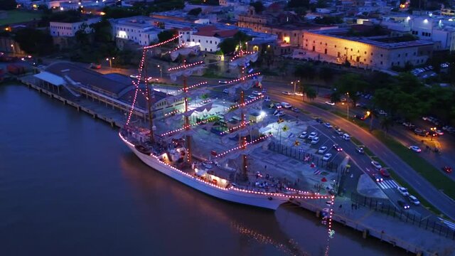 Scenic aerial view of training ship Juan Sebastian de Elcano, brig-schooner of Spanish navy docked at Puerto Don Diego at night, Santo Domingo, Dominican Republic, circle aerial