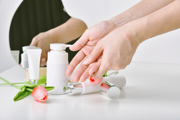 Obraz na płótnie Canvas Hand applying natural skincare, Cosmetic bottle containers packaging with tulip flower essence, Organic beauty product concept.