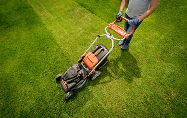 Gardener mowing the lawn. Landscape design. Green grass background
