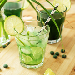 Refreshing chlorella lemonade with lime on a wooden table.