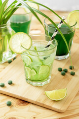 Refreshing chlorella lemonade with lime on a wooden table.