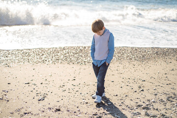 The baby boy walks along the sandy beach along the coast.