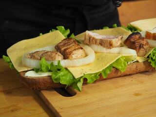 the chef slices and puts the meat on a mega sandwich with salad leaves.