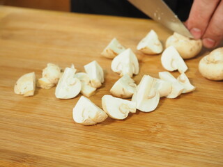 the cook slices the mushrooms with a knife on a wooden Board. slicing mushrooms