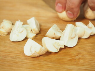 the cook slices the mushrooms with a knife on a wooden Board. slicing mushrooms