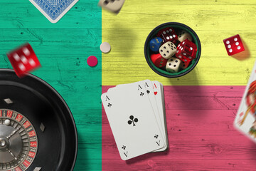 Benin casino theme. Aces in poker game, cards and chips on red table with national flag background....