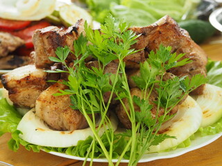 pork skewer with a bunch of fresh parsley on a plate. ready-made grilled meat.
