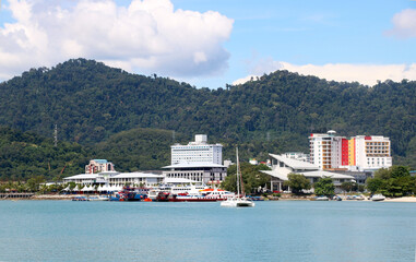 view of hotel and building and ship standing near beach with background of green hills with trees and blue sky with cloud at langkawi malaysia