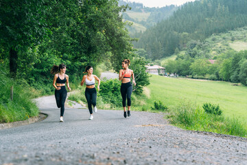 three girls running down a road through the woods