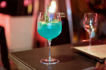 Cocktail with gin, blue curaçao, rosemary, ice, lime and tonic water