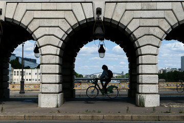 Silhouette of a cyclist passing under the Bercy Bridge.